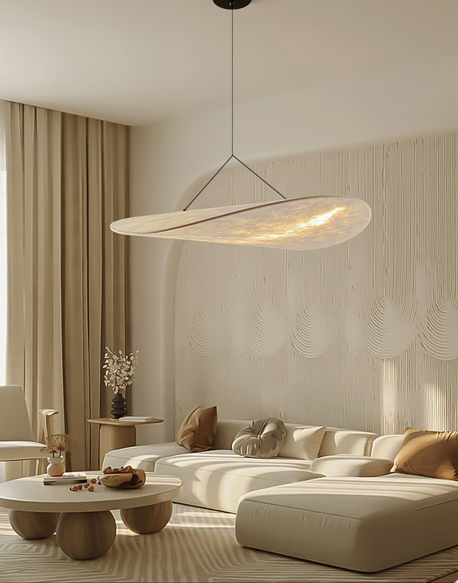 Modern living room with a pendant light, beige sofa, and decorative elements.